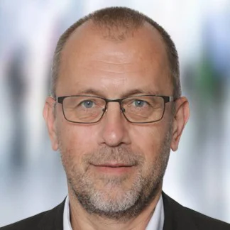 Portrait von Günther Strauch, ein Mann mittleren Alters mit Brille und sehr kurzen Haaren