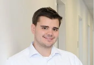 Portrait von Stefan Renner, junger Mann mit dunklen Haaren und einem weißen Hemd